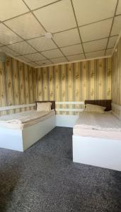 two beds in a room with wooden walls at Мурас хостел in Var-Kyshtak