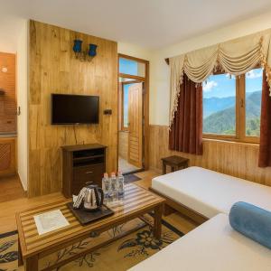 a room with a bed and a tv and a table at Manu Villa Manali - A Beautiful Cottage towards Snow Capped Mountain in Manāli