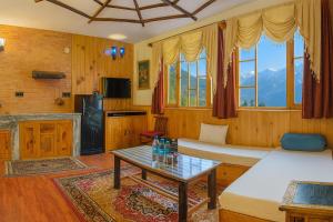 a living room with two beds and a table at Manu Villa Manali - A Beautiful Cottage towards Snow Capped Mountain in Manāli +27 photos