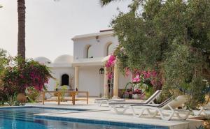 a villa with a swimming pool in front of a house at Dar 'Villa Blanche' in Djerba