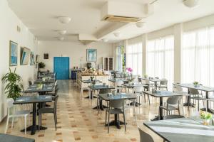una fila di tavoli e sedie in una stanza con finestre di Arix Hotel a Rimini
