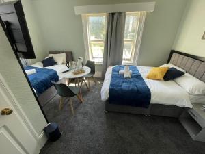 a bedroom with two beds and a table and a tv at The Kirkdale Hotel in Croydon +14 photos