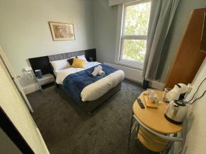 a bedroom with a bed with a stuffed animal on it at The Kirkdale Hotel in Croydon