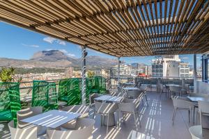 ein Restaurant mit Tischen und Stühlen und Bergblick in der Unterkunft Hotel Madeira Centro in Benidorm