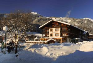 a large building in the snow in front of a mountain at Hotel Bergland in Lermoos