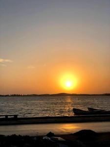 a sunset over the water with two boats on the beach at Varanda Atlantica Casa Camocim enfrente a praia in Camocim