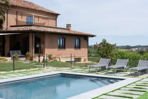 a villa with a swimming pool in front of a house at Da Elvira in Costigliole dʼAsti