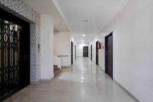 a hallway with black doors and white walls and white tiles at Hotel Aditya Grand in Guntūr