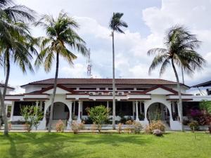a building with palm trees in front of it at Bunga Raya Resort Parit Buntar in Parit Buntar