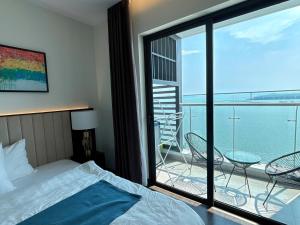 a bedroom with a bed and a balcony with a view at Sapphire Premium Studio Hạ Long in Ha Long +40 photos