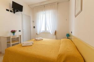 una camera da letto con un letto giallo con due asciugamani sopra di Arix Hotel a Rimini