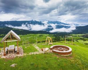 a cow standing in a field next to a field with a hill at David traditional Oda in Shuakhevi +17 photos
