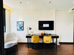 a dining room with a table and yellow chairs at Sapphire Premium Studio Hạ Long in Ha Long
