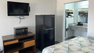 a room with a black refrigerator and a tv at Studio 6 Suites Opelousas, LA in Opelousas