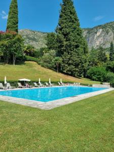 a swimming pool in a park with chairs and trees at Princess Night con piscina in Griante Cadenabbia +15 photos