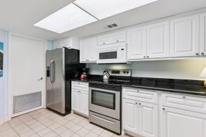 a kitchen with white cabinets and a stainless steel refrigerator at North Breakers 201 in Saint Simons Island +27 photos