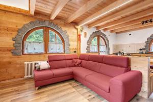 a living room with a red couch in a room with wooden ceilings at Maso Rubino in Rabbi