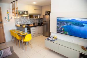 a kitchen with a table and a tv on a wall at Flat Resort Beira Mar Porto de Galinhas in Ipojuca