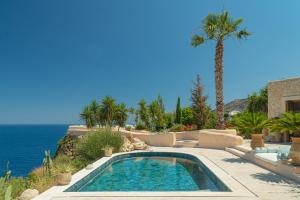 a swimming pool in a yard with a palm tree at Villa Mirabello Tholos Adults Only in Kavoúsion