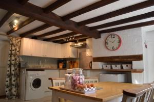 a kitchen with a table and a clock on the wall at The Cottage in Sulgrave