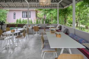 a restaurant with white tables and chairs and trees at Boonya Swiss Home in Chaloklum
