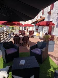 an outdoor patio with tables and chairs and umbrellas at Auberge de la Belette in Le Monestier