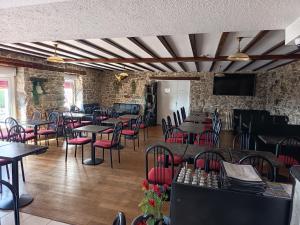a restaurant with tables and chairs and a tv at Auberge de la Belette in Le Monestier