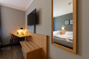 a hotel room with a mirror and a bed at Garner Hotel Cottbus Süd by IHG in Cottbus +134 photos