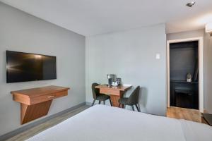 a hotel room with a bed and a desk and a tv at Motel Newstar Laval in Laval