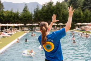 a woman standing in a swimming pool with her hands in the air at Club del Sole Due Laghi Levico Family Collection in Levico Terme