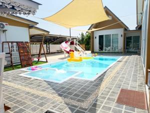 a backyard with a pool with a swing and an umbrella at My friend private pool villa in Samut Songkhram