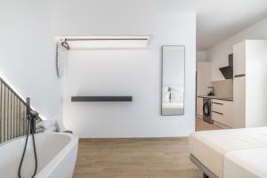 a white bathroom with a bath tub next to a bed at Apartamentos Surya Home Suites in Conil de la Frontera +48 photos