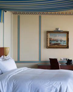 a bedroom with a bed and a desk and a picture at Rosewood Jeddah in Jeddah