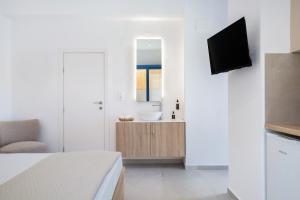 a white bathroom with a sink and a television at Khōra Suites Matala in Matala