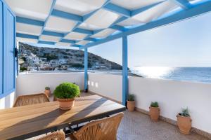 a balcony with a wooden table and chairs and the ocean at Khōra Suites Matala in Matala
