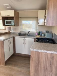 a kitchen with white cabinets and a counter top at Dotties Den at Sunnysands in Llanddwywe +8 photos