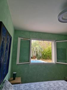 a bedroom with a green wall with a window at Chez raymonde in Teyran +1 photo