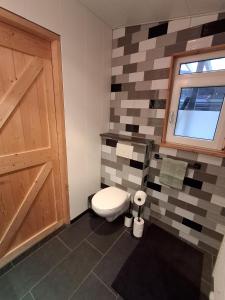 a bathroom with a toilet and a window and a door at Guesthouse Bij Maud in Barsingerhorn