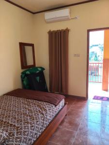 a bedroom with a bed and a door to a balcony at Penginapan Griya Safira in Taliwang