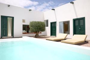 a white house with a swimming pool and two chairs at Casa Montelongo - Adults Only in La Oliva