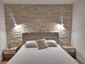a bedroom with a white bed with a brick wall at Savo Apartments in Tivat