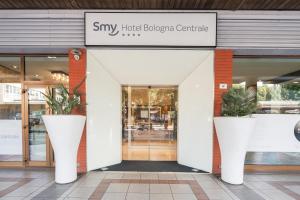 a store front with two large white pots with plants at Smy Bologna Centrale in Bologna