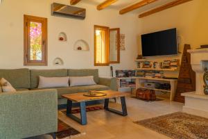 a living room with a couch and a tv at Villa Mirabello Tholos Adults Only in Kavoúsion