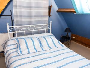 a bed with a white and blue striped comforter at gite 618 in Helfaut