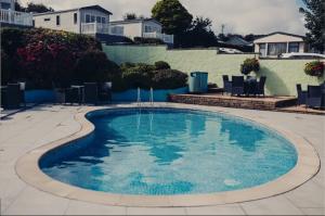 a swimming pool with blue water in a yard at Caravan 68 The Vale in Fishguard