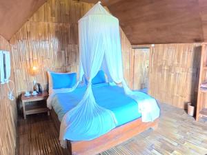 a bedroom with a blue bed with a canopy at Wanagiri sunset glamping in Gitgit