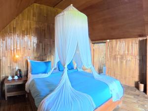 a bedroom with a blue bed with a canopy at Wanagiri sunset glamping in Gitgit +46 photos