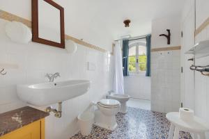 a white bathroom with a sink and a toilet at Villa Le Ginestre di mare in Capoliveri +32 photos