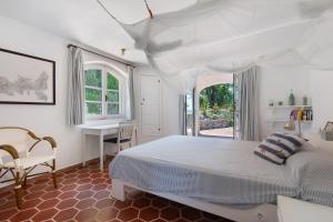 a white bedroom with a bed and a desk at Villa Le Ginestre di mare in Capoliveri