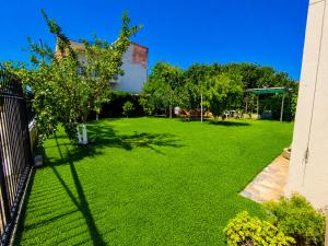 a large green yard with trees and a building at Angela's House in Nea Plagia